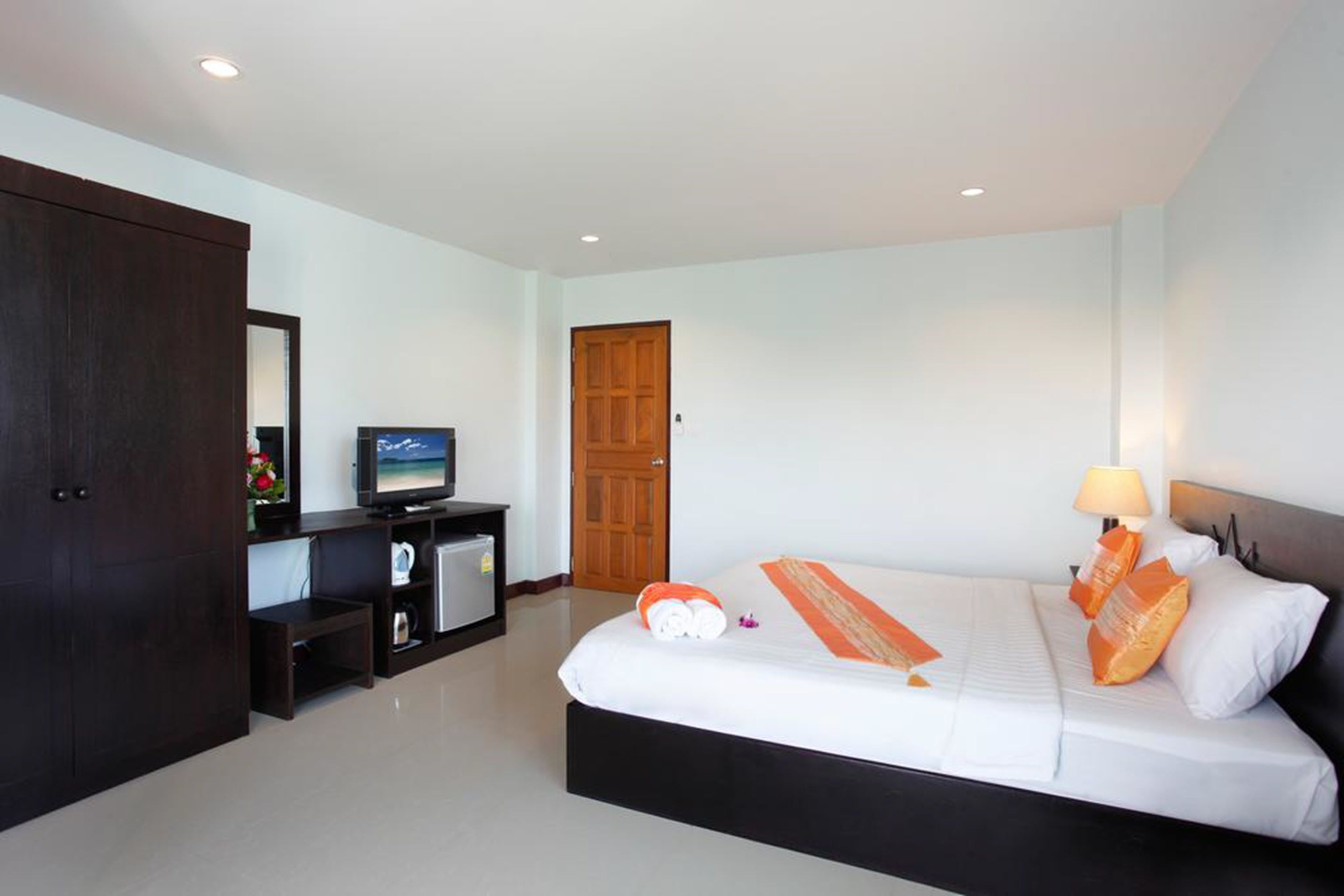 Una habitación de hotel con una cama, televisión, escritorio con computadora y armario.