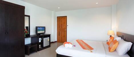 Una habitación de hotel con una cama, televisión, escritorio con computadora y armario.