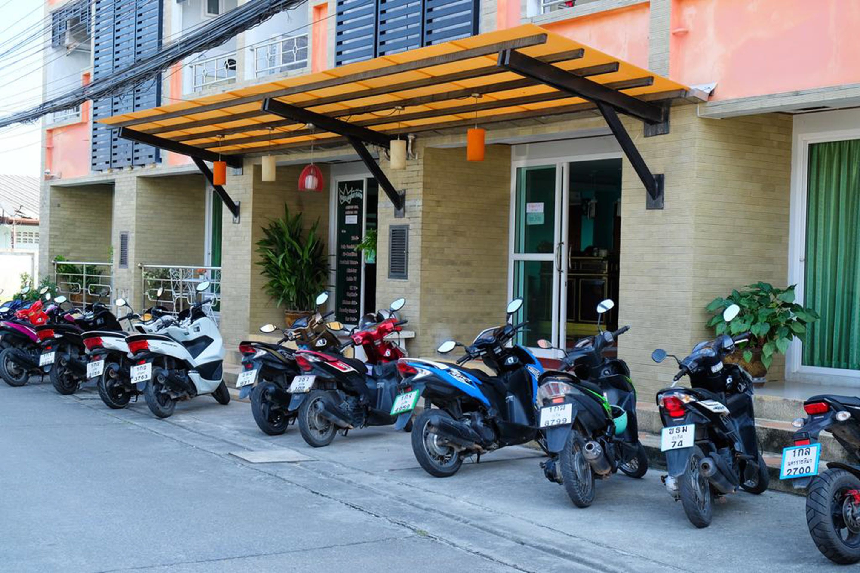 A row of motorcycles parked in front of a building with a covered area.