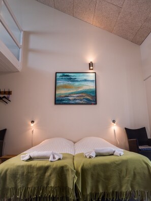 A hotel room with a bed, two bedside lamps, a painting on the wall, and a window with blinds.