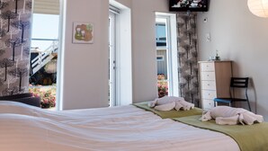 A bedroom with a bed, a dresser, a television on the wall, and a window with curtains. - Oldfruen De luxe (Vaeggerlose)