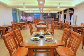 A dining area with multiple wooden tables and chairs, arranged in a spacious layout. - Glorious Monywa Hotel (Monywa)