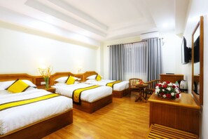 A hotel room with two single beds, a wooden desk, a chair, a small table, and a TV mounted on the wall. - Glorious Monywa Hotel (Monywa)