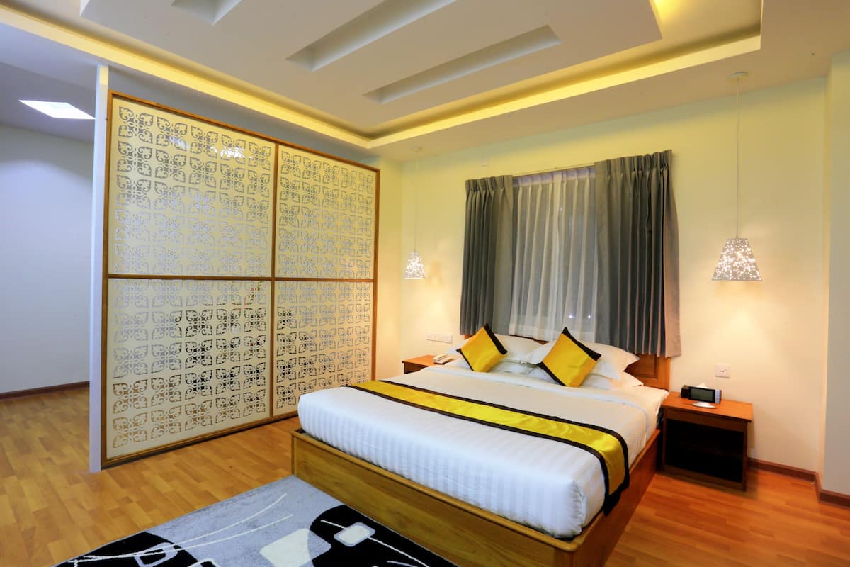 Ein modernes Hotelzimmer mit einem großen Bett, einem Holz-Kopfteil, einer dekorativen Trennwand und zwei Nachttischlampen.