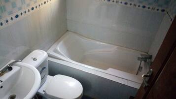 A small bathroom with a bathtub, toilet, and sink.