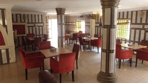 Un restaurante con sillas y mesas rojas, piso de baldosas y paredes a rayas.