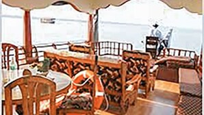 A dining area with wooden furniture and a view of the sea. - GuestHouser 3 BHK Houseboat e567 (Kuttanad Taluk)