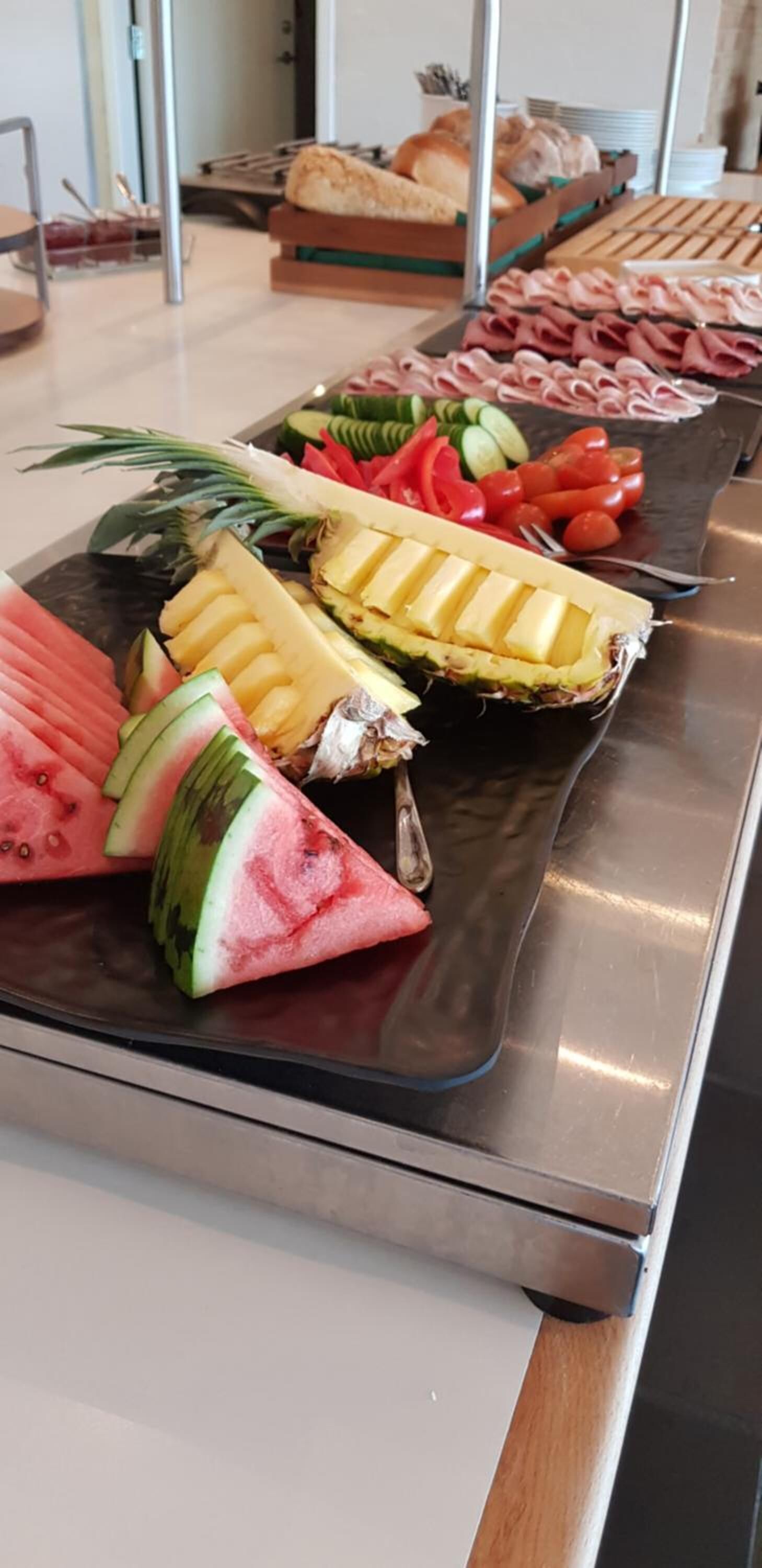 A buffet table with various fruits, vegetables, and meats.