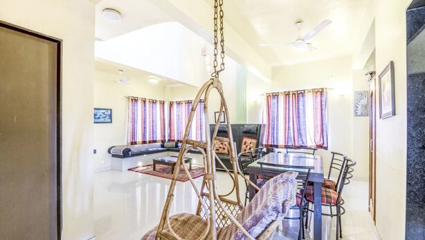 A spacious living area with a swing chair, a dining table with chairs, and a sofa. - GuestHouser 3 BHK Bungalow c477 (Mawal)