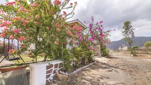 A residential area with a house, a dirt road, and flowering plants. - GuestHouser 3 BHK Bungalow c477 (Mawal)