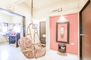Una habitación con una silla colgante, un lavamanos, un espejo y una puerta con un cuadro enmarcado.