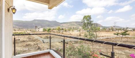 Un balcón con vistas a un paisaje rural, incluyendo colinas y vegetación escasa.
