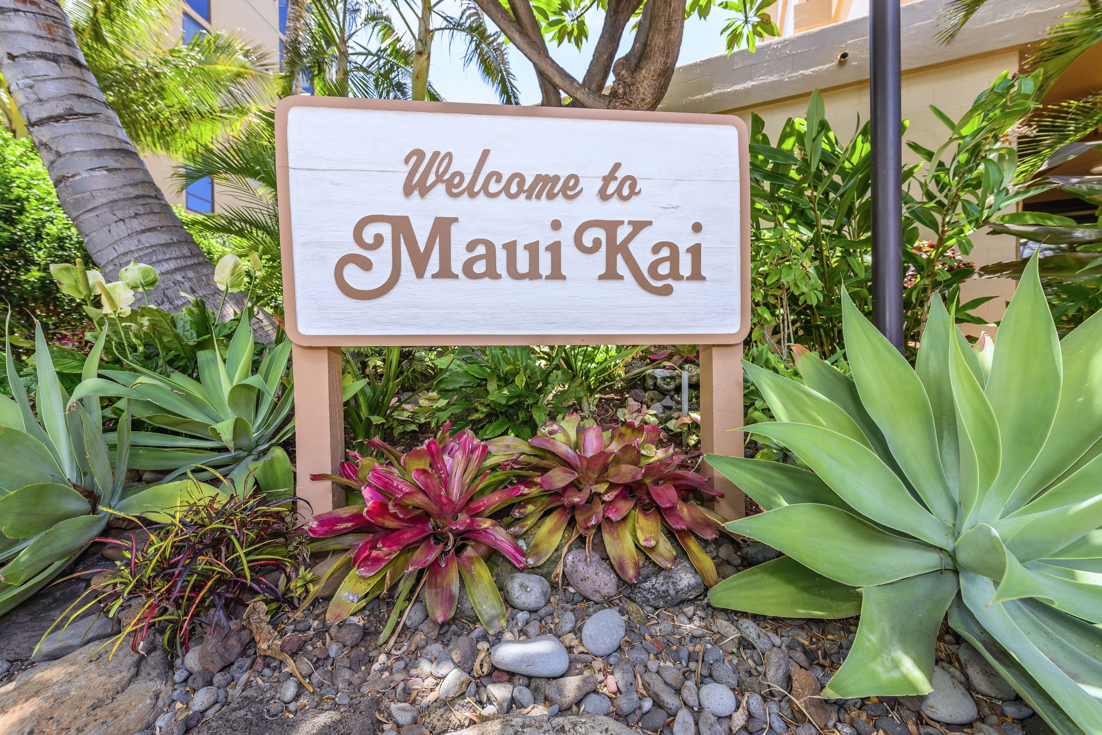 Un panneau d’accueil accueillant les visiteurs du Maui Kai, entouré de plantes tropicales.