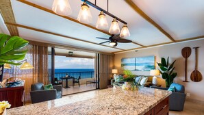 A modern kitchen with a granite countertop, a ceiling fan, and pendant lights.