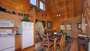 Ein Blockhaus-Interieur mit Küche, Essbereich und Kamin.