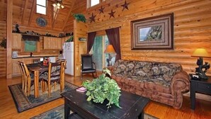 Ein Holzblockhaus-Innenraum mit Essbereich, einer Couch und einem Bild an der Wand.