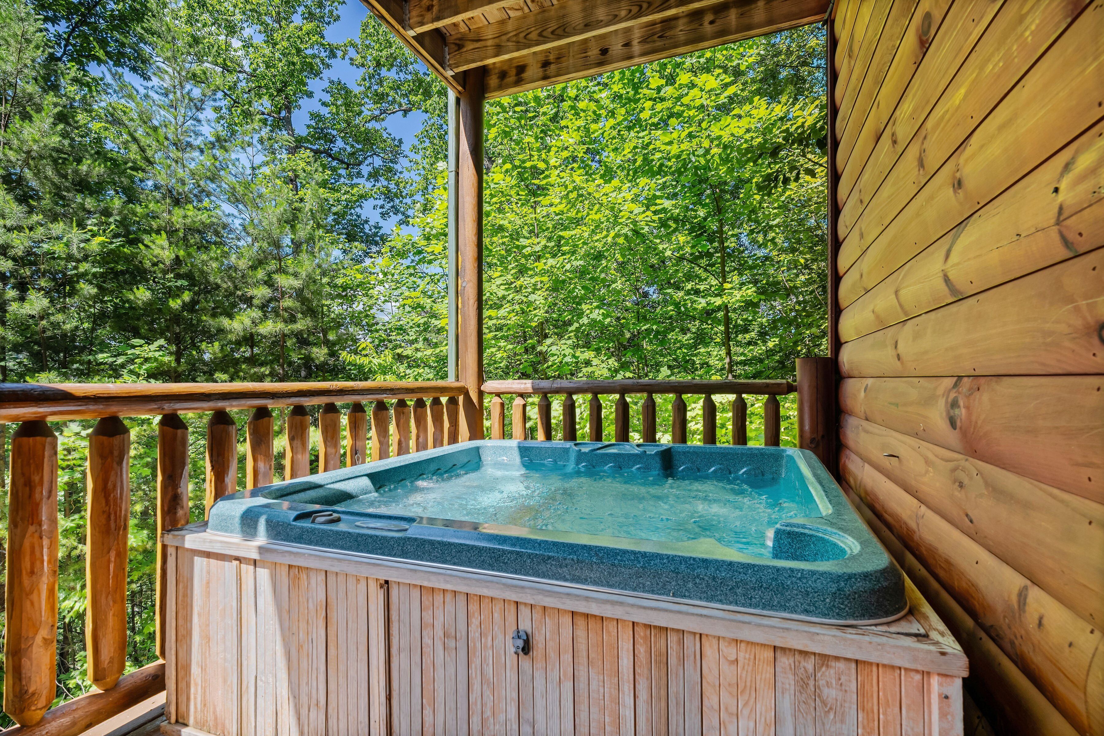 Un bain à remous en bois installé sur une terrasse dotée d’une balustrade en bois, le tout entouré d’arbres.