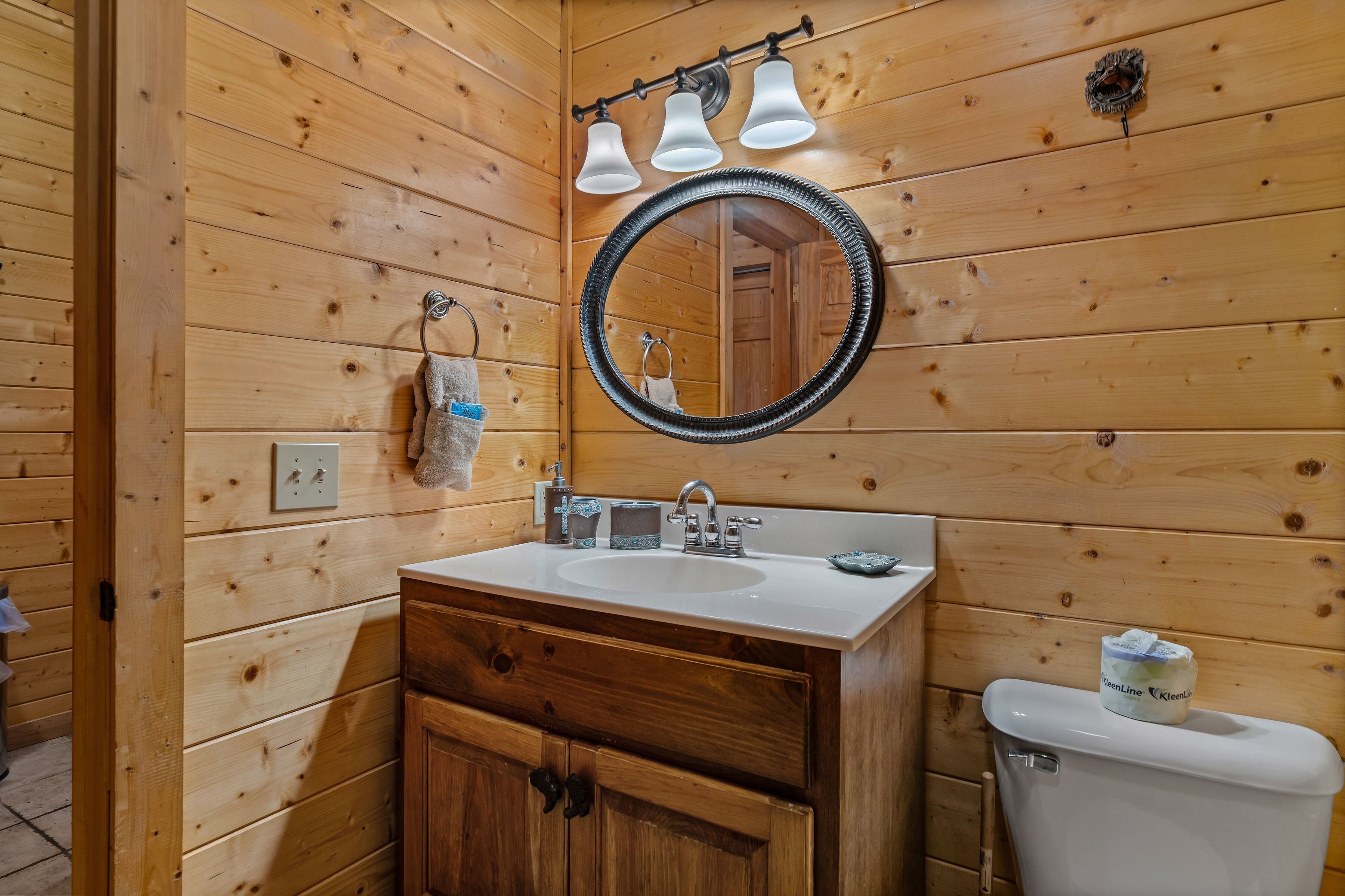 Baño de cabaña de madera con lavabo, espejo y retrete.