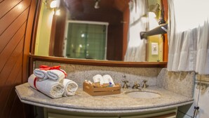Een badkamer met houten lambrisering, een wastafel met spiegel, handdoeken, een douche en een toilet.