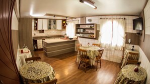 Een kleine keuken met houten kastjes, een centraal eiland en een eethoek met vier stoelen en een tafel.