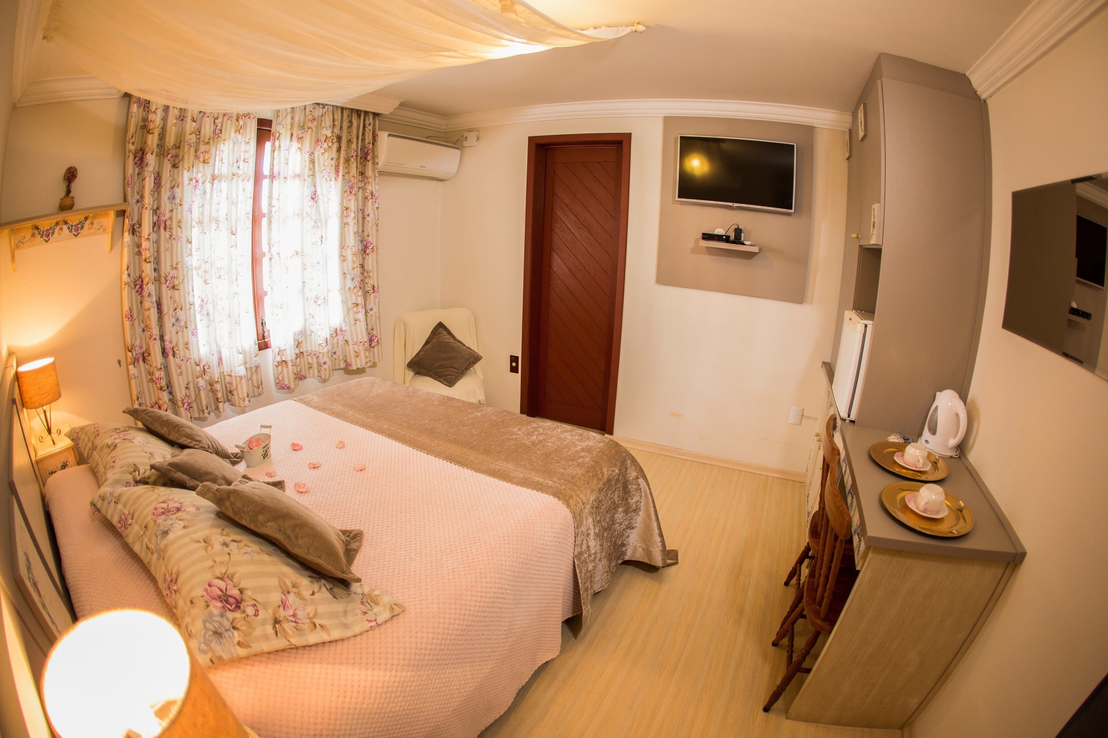 Un dormitorio con cama, televisor, cómoda y espejo.