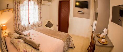 Un dormitorio con cama, televisor, cómoda y espejo.