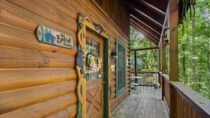 A wooden cabin with a wooden door, a sign reading "The Board Family," and a porch with outdoor seating. - Forest Fling 2 Bedroom Cabin by RedAwning (Sevierville)