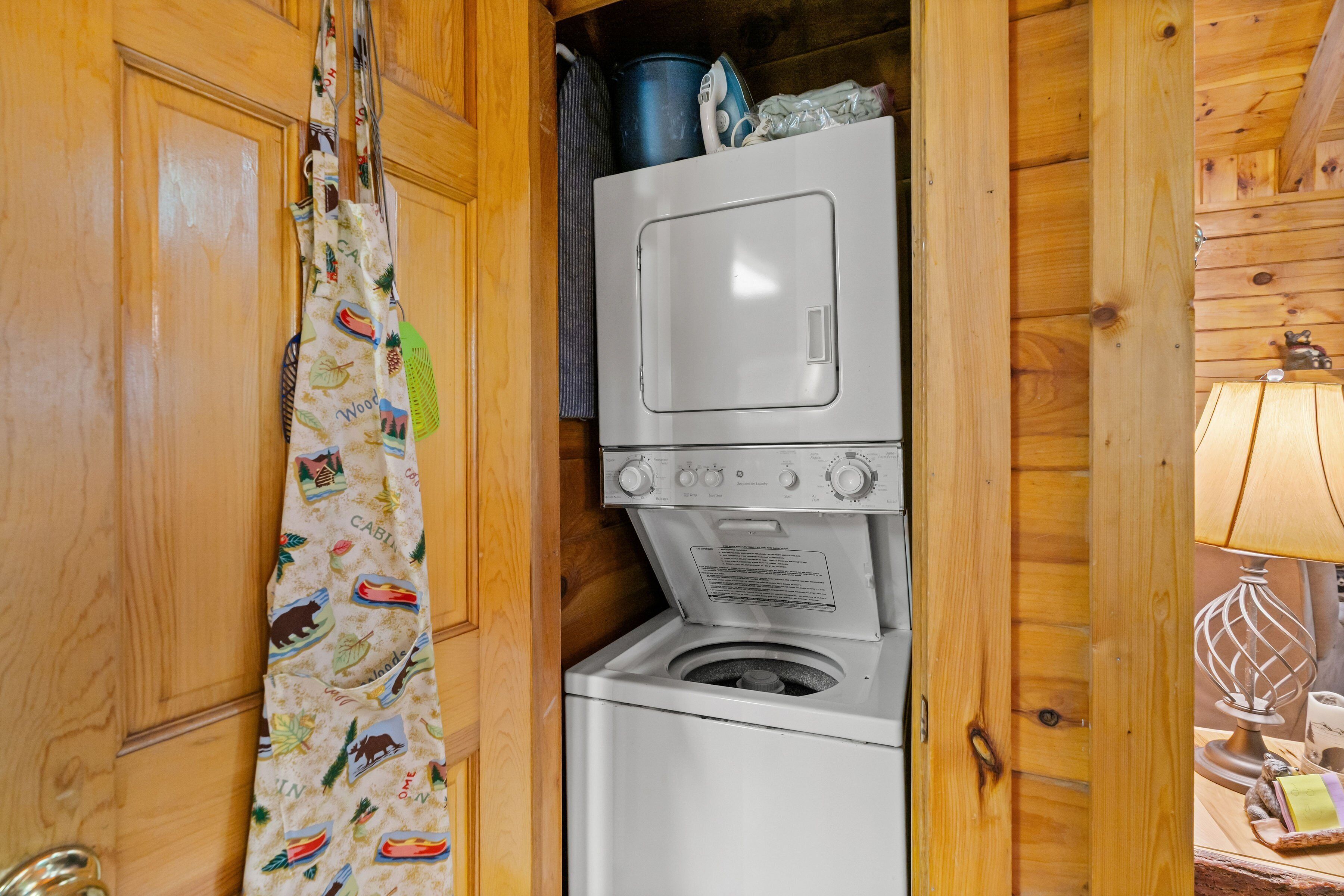 A compact laundry area with a washing machine and dryer stacked in a wooden cabin.