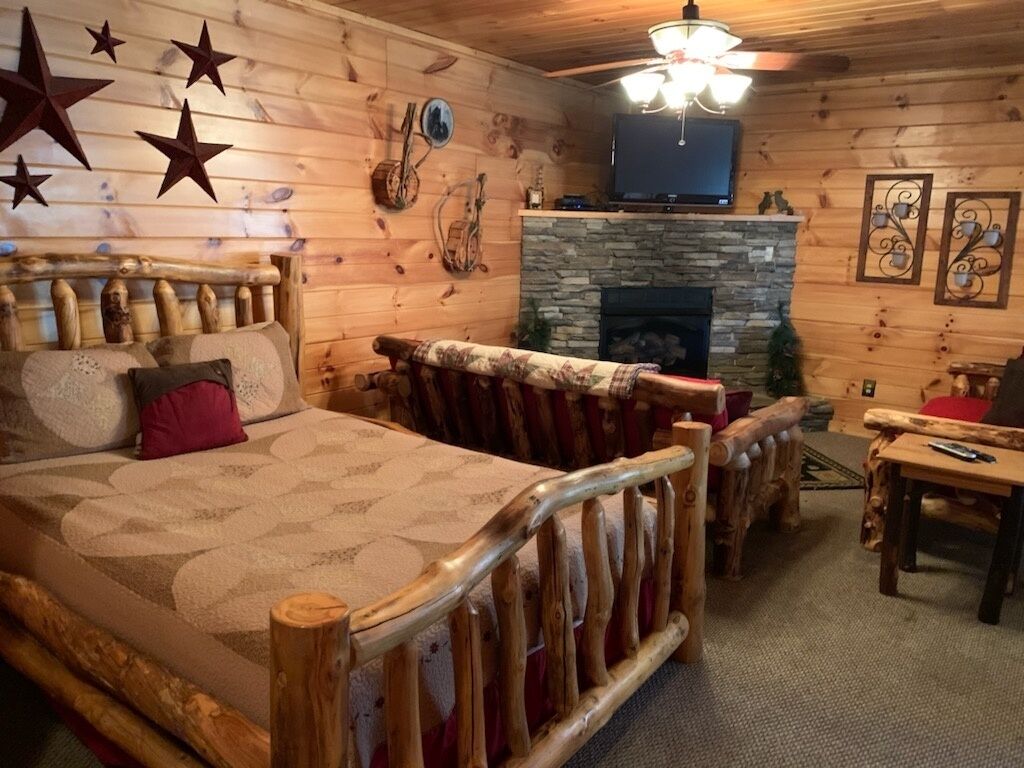 A log cabin room with a bed, a fireplace, and a television.