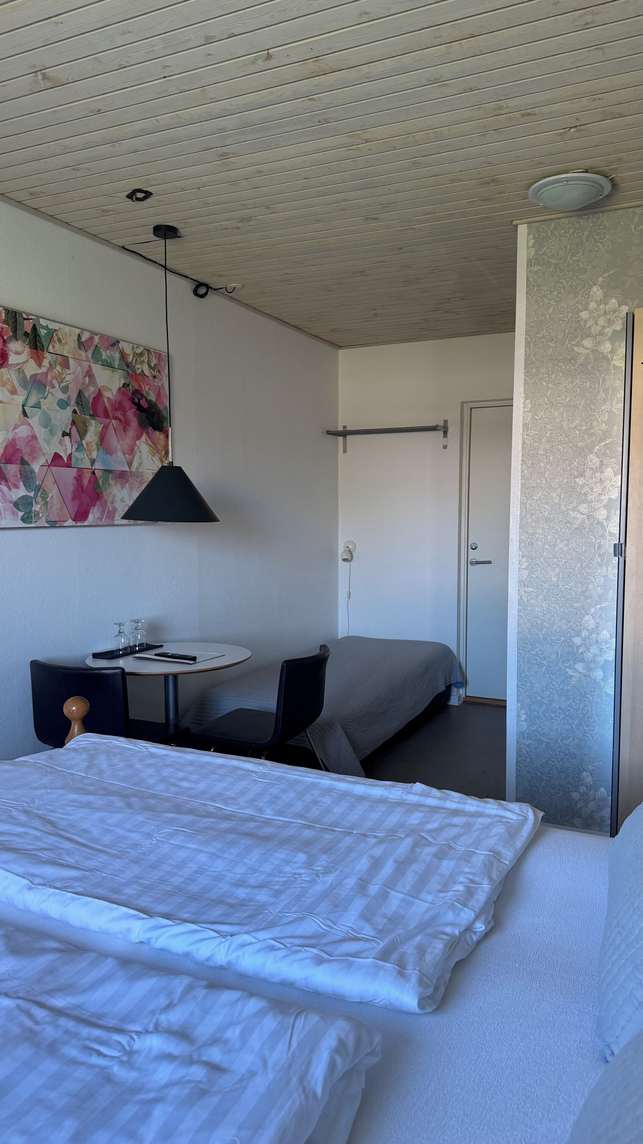 Una camera da letto con un letto, una scrivania, una sedia, una lampada e una porta.