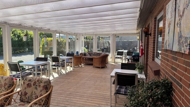 A covered patio area with outdoor furniture, a table, and chairs. - Hine Bakke Guest House (Rudkobing)