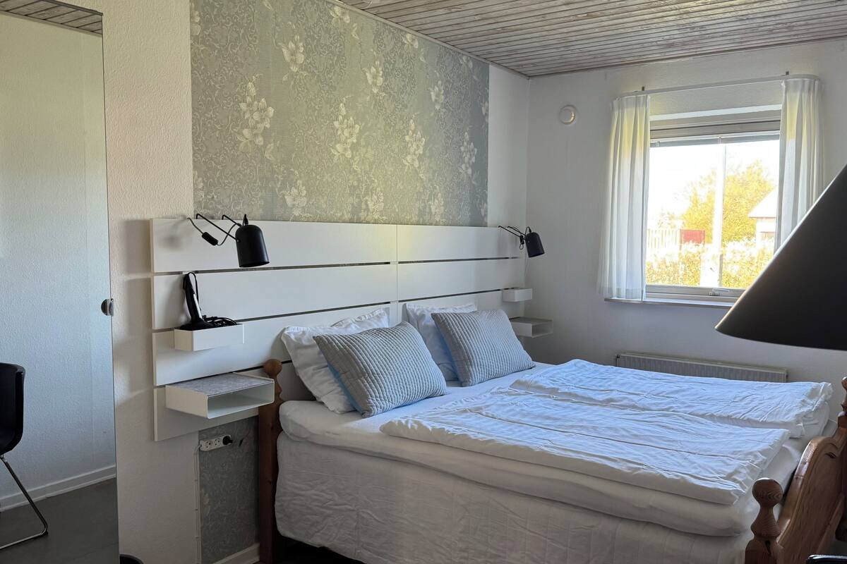Ein Schlafzimmer mit einem Bett, Nachttischlampen, einem Fenster und einer Heizung.
