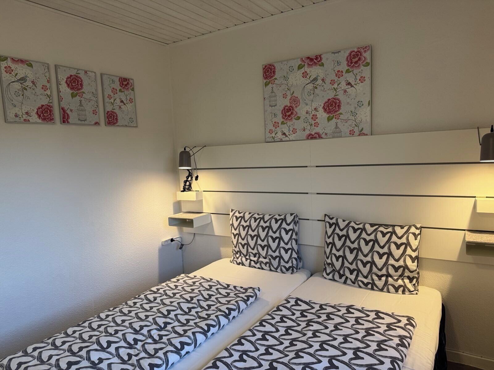 Un dormitorio con cama, mesitas de noche y decoración en la pared.
