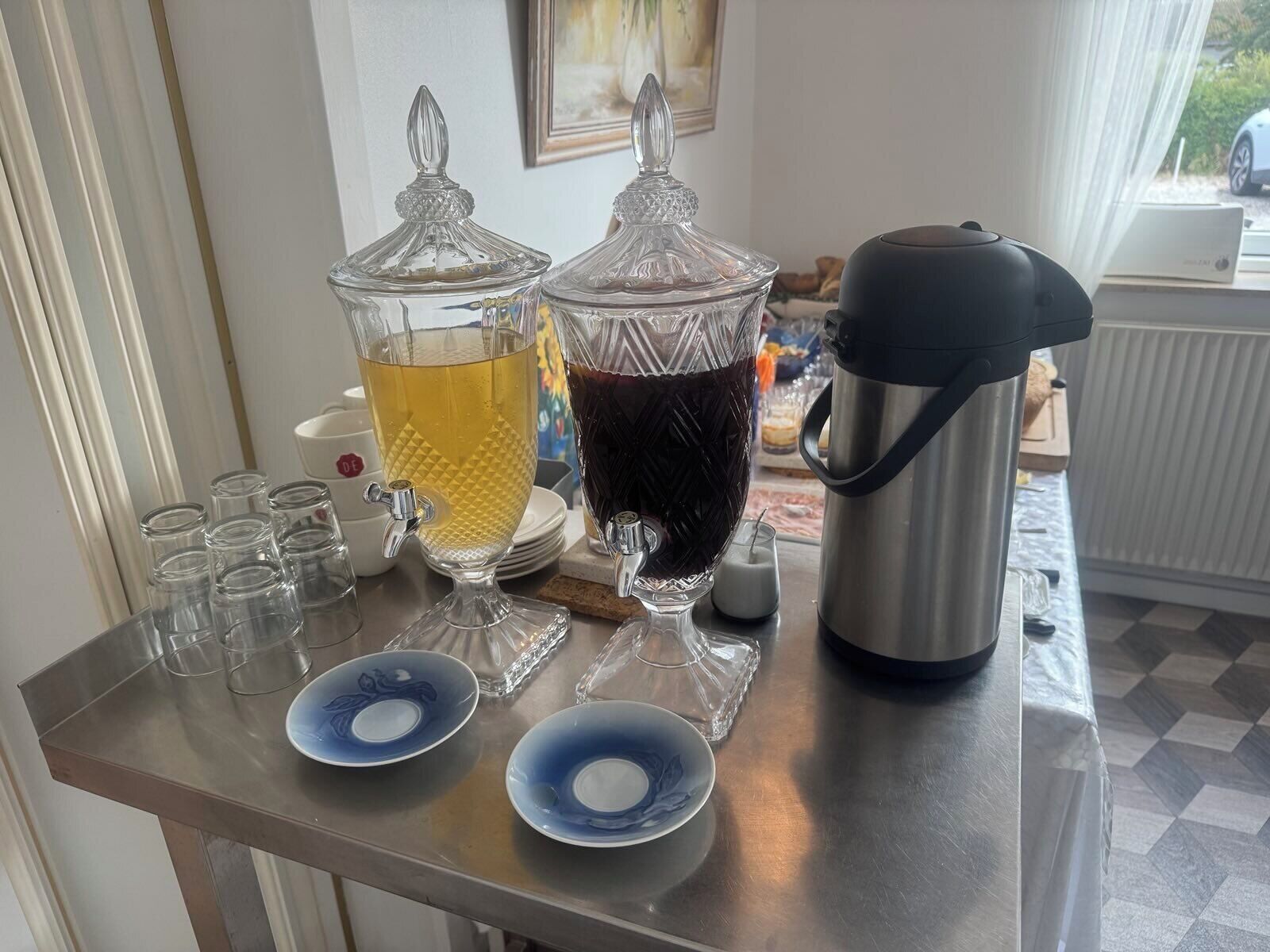 A bar area with two glass dispensers, a coffee maker, and a selection of glasses and plates.