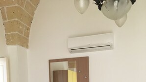Ein Zimmer mit Holzschrank, kleinem Tisch und Wandgerät zur Klimatisierung.