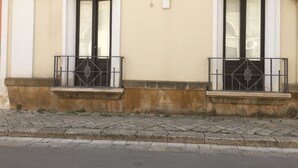 Eine Gebäudefassade mit zwei Fenstern, jedes mit einem kleinen Balkon und einer dekorativen Statue darüber.