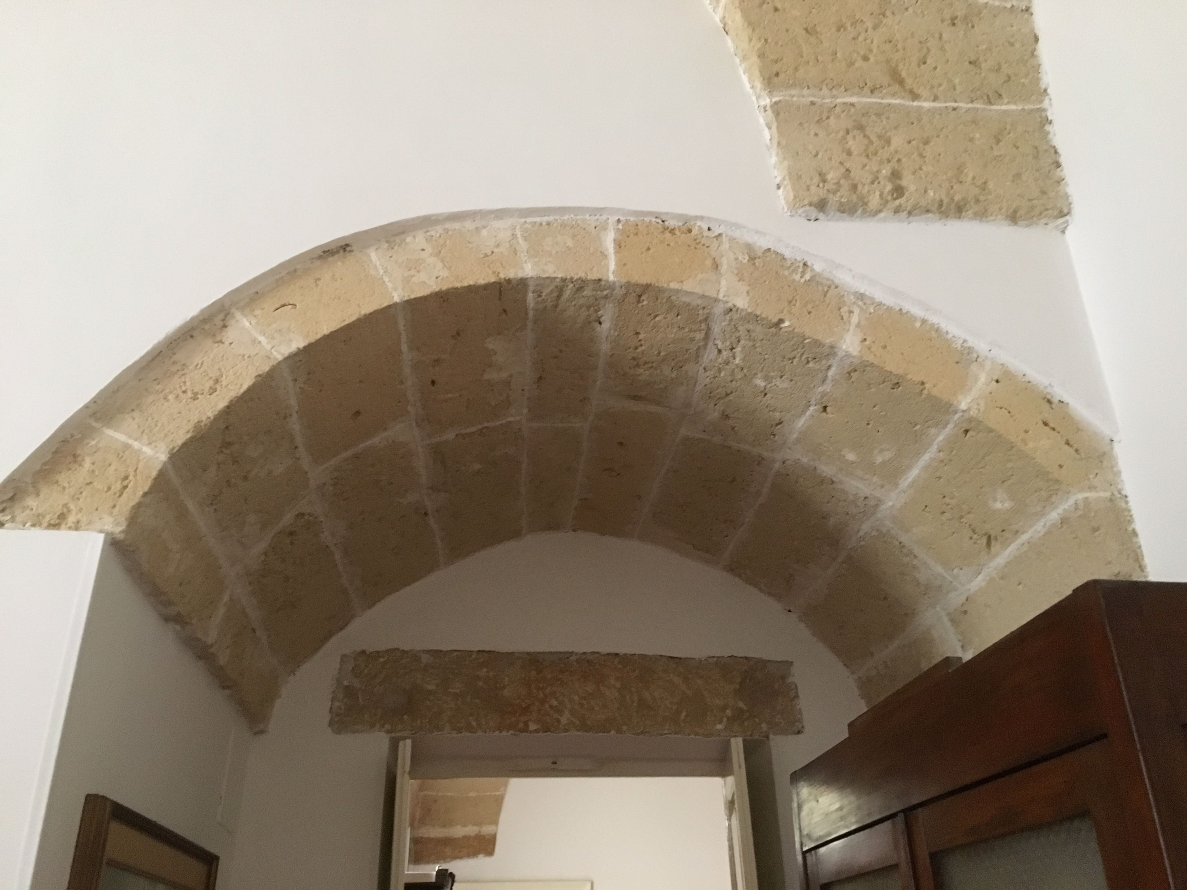 Un arco ad arco in pietra e una parete bianca.