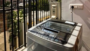 Un tostador LG moderno y compacto en un balcón, con vistas a un paisaje urbano a través de barandillas metálicas.