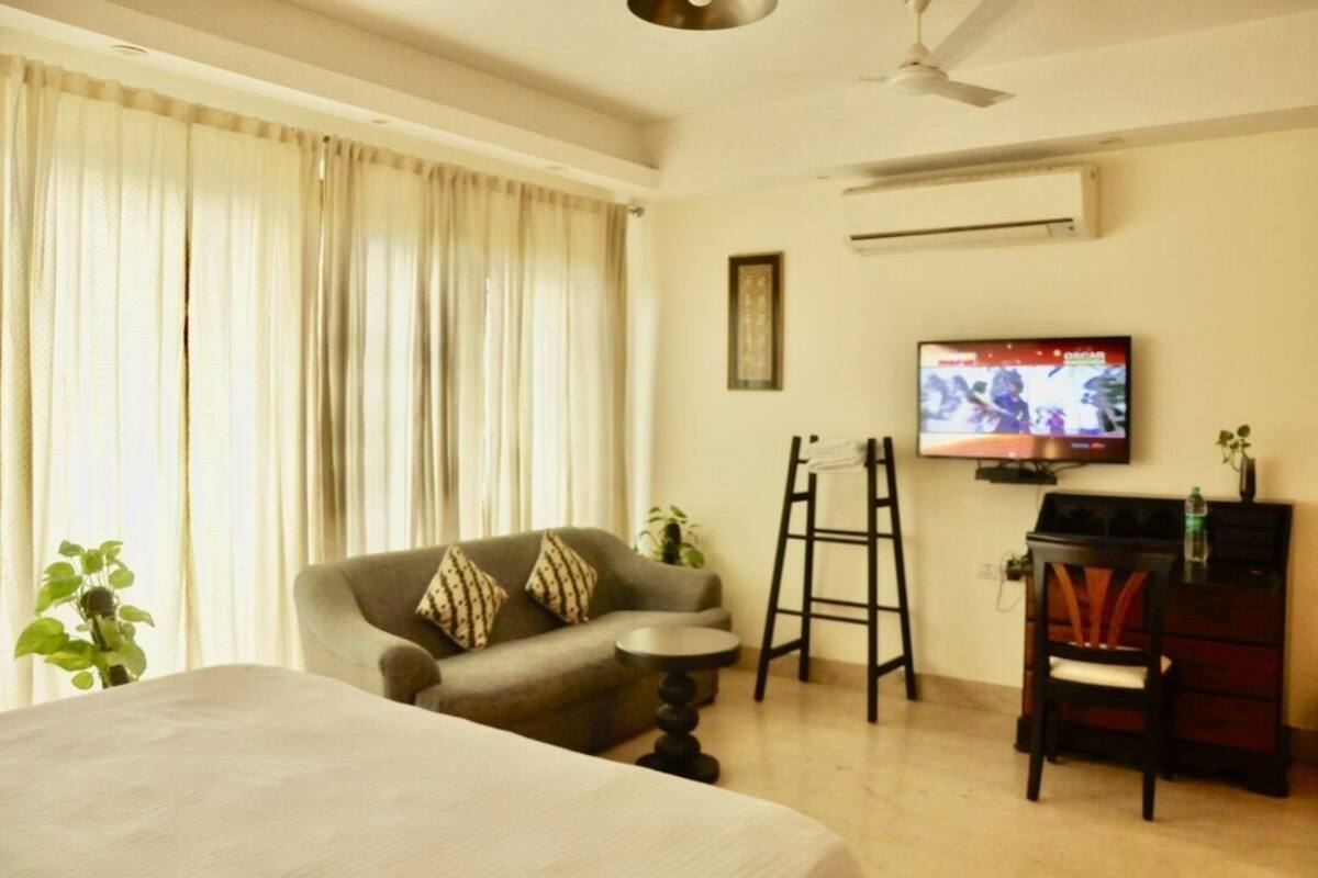 A hotel room with a bed, a sofa, a small table, a TV, and a desk with a chair.