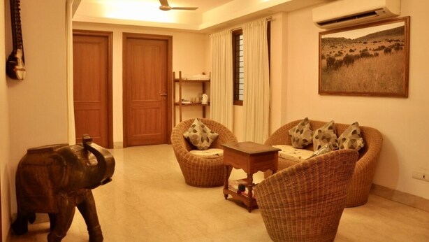 Un salón con dos sofás de mimbre, una pequeña mesa de madera y una estatua decorativa de un elefante.