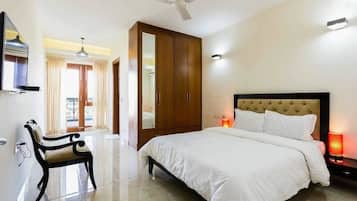 A bedroom with a bed, a wardrobe, a chair, and a TV.