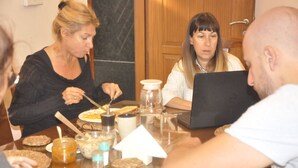 Un grupo de personas sentadas alrededor de una mesa con comida y un ordenador portátil.