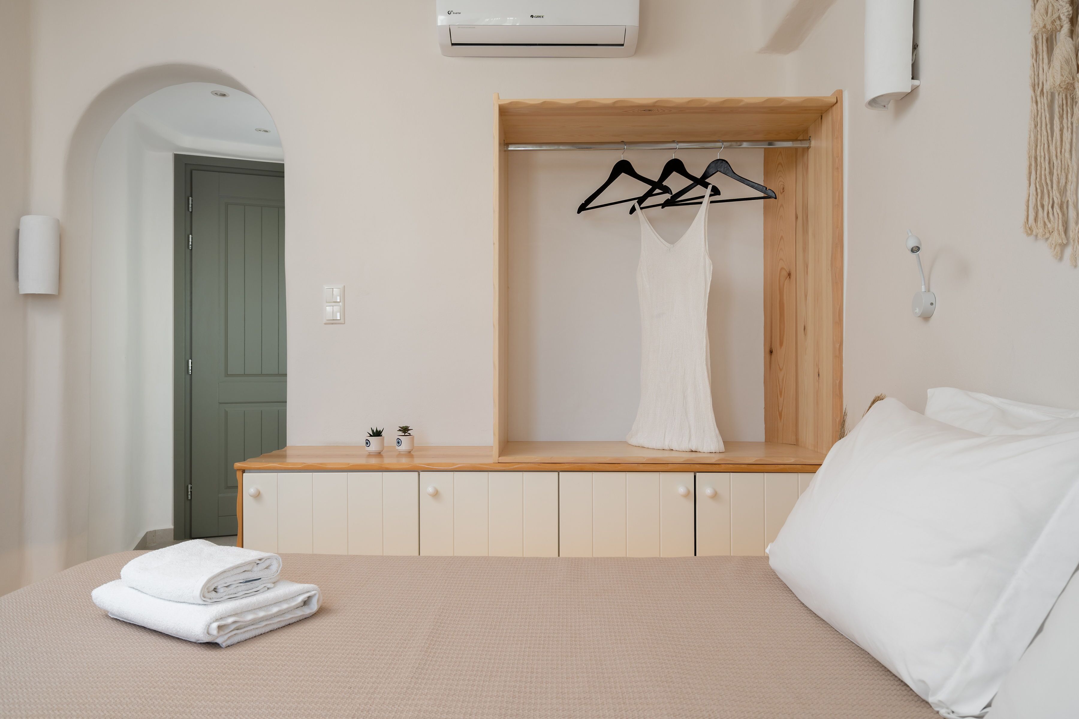 Ein Schlafzimmer mit einem Bett, einem Holzschrank, einem Kleiderständer und einer grünen Tür.