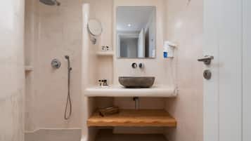A bathroom with a shower, a sink with a bowl, a mirror, and a towel rack.