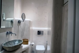 Un baño con un lavabo de piedra, un espejo, un inodoro y una ducha.