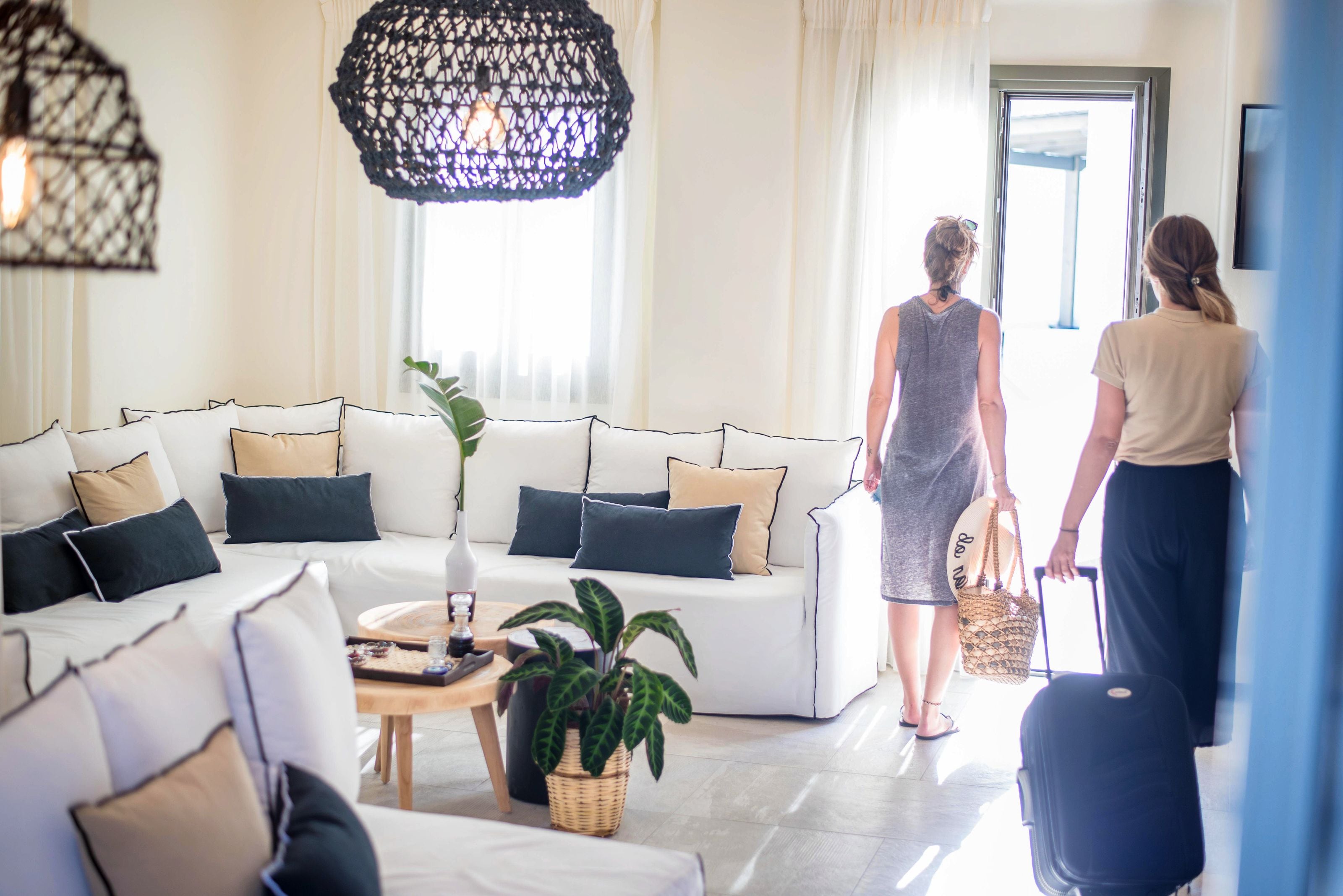 A modern living room with a white sofa set, a coffee table, and a large woven light fixture.