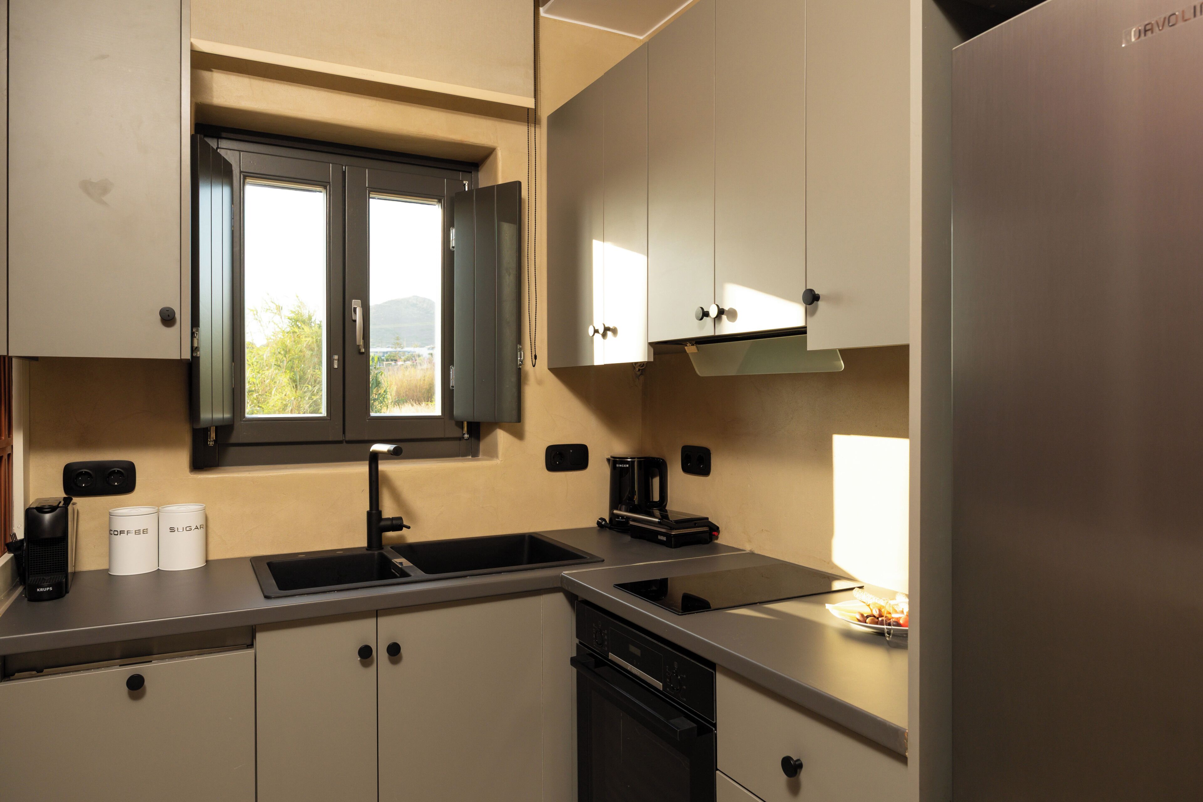 A kitchen with a double sink, a coffee maker, and cabinets.