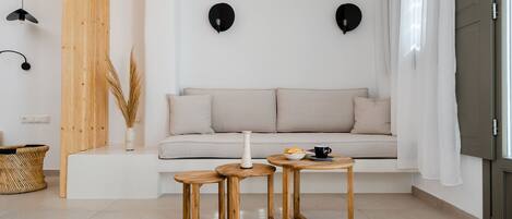 A modern living room with a sofa, two wooden side tables, a vase, and a basket.
