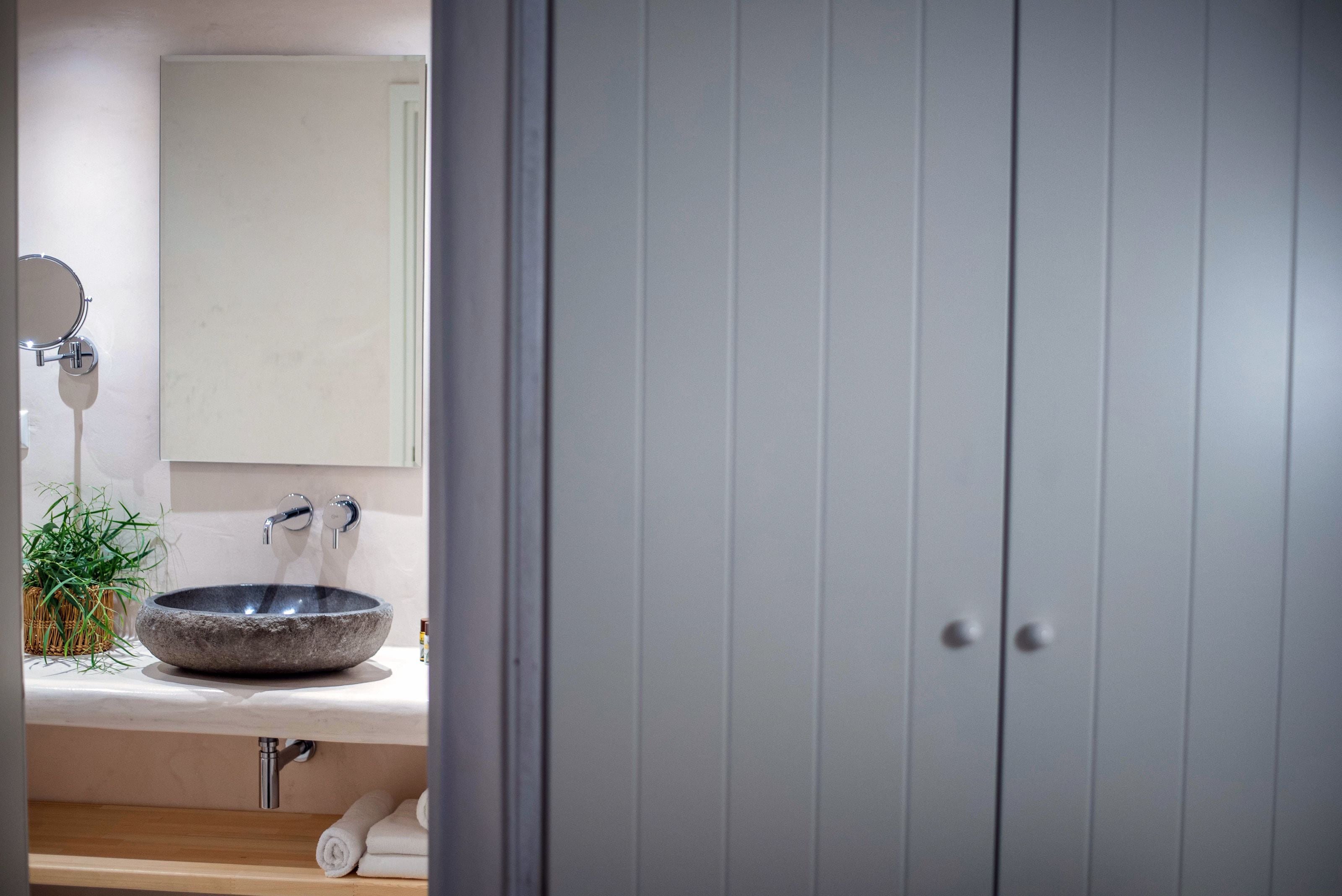 Un baño con un lavabo de piedra, un espejo y un perchero para toallas.