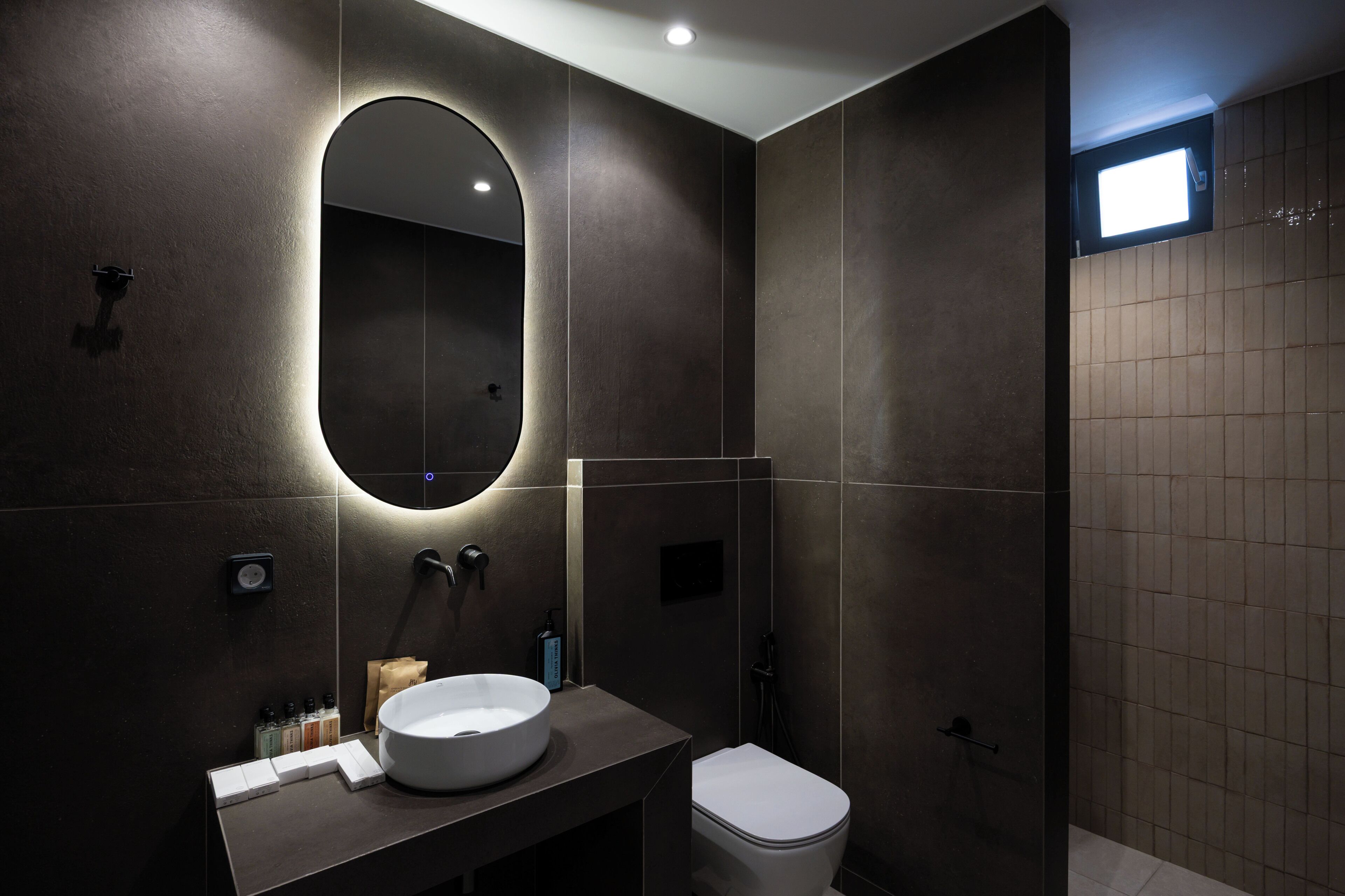 A modern bathroom with a round mirror, a sink, and a toilet.